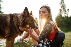 Young beautiful woman petting her cute dog in park